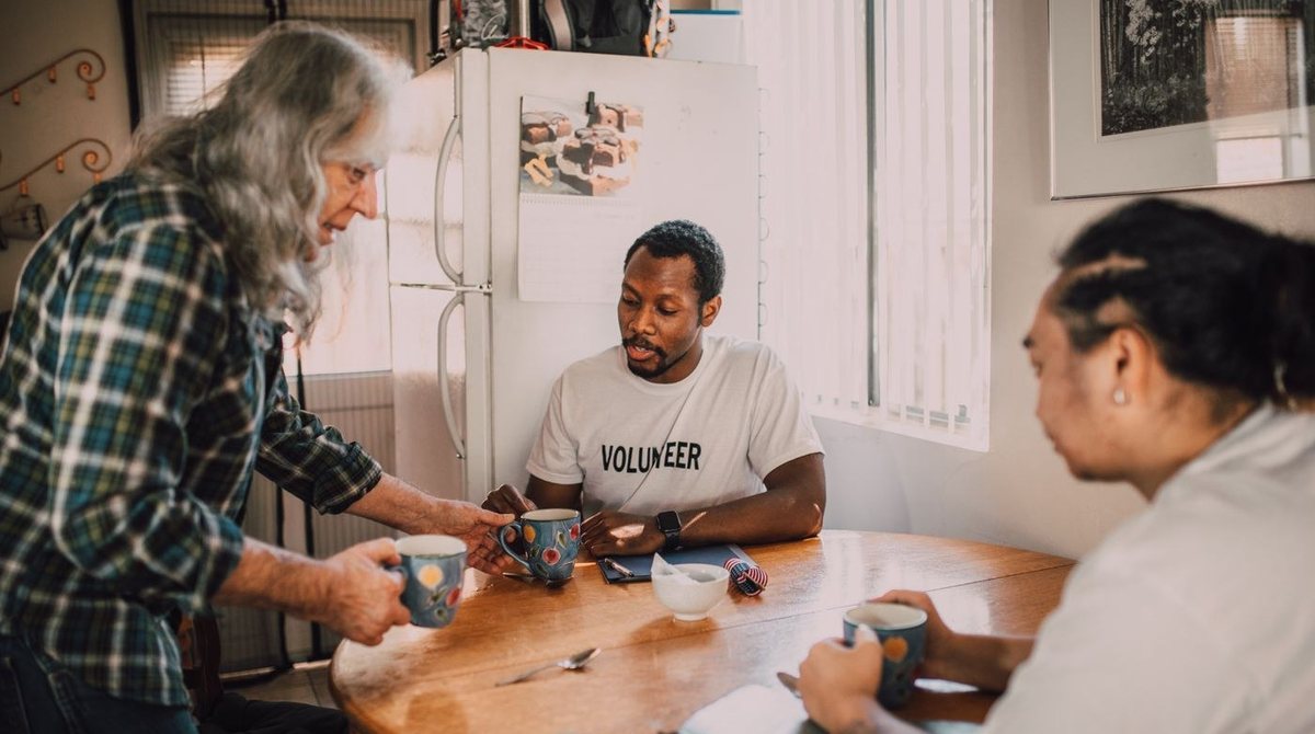 Volunteers talking together around a kitchen table.